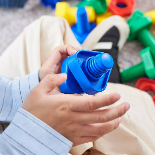 Child's hands holding a blue plastic block with colorful building blocks in the background